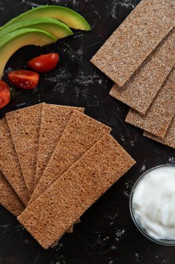 Kepekli çavdar crispbread kraker ile siyah arka plan üzerine sandwicht için malzemeler ile gelen sağlıklı snack