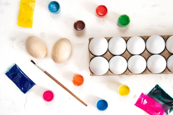 Яйца и краски на белом фоне. Раскрашивание пасхальных яиц — стоковое фото