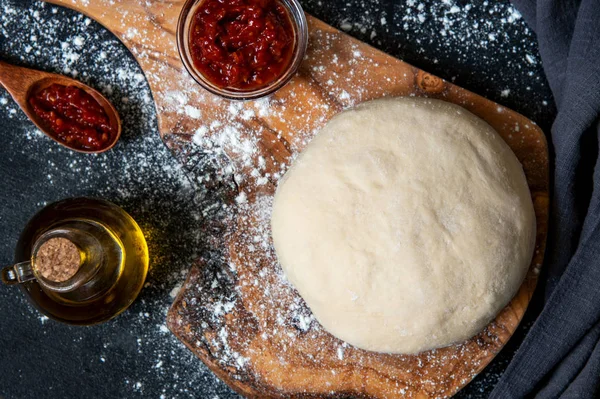 Preparación de masa cruda o pizza con ingrediente: salsa de tomate, aceite de oliva. Estilo laico plano —  Fotos de Stock