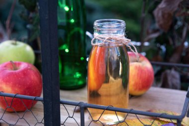 Taze elma suyu şişede, tahta tepside, açık havada.
