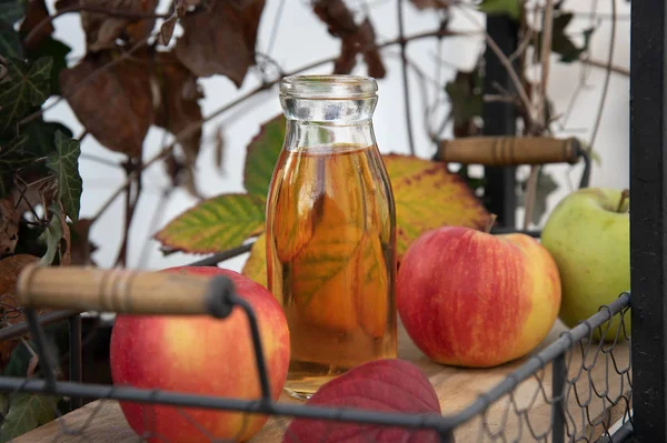 Jugo de manzana fresca en la botella en la bandeja de madera, al aire libre — Foto de Stock