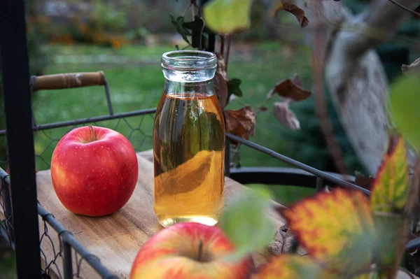 Fresh apple juice in the bottle on the wooden tray, outdoor — Stock Photo, Image