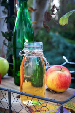 Taze elma suyu şişede, tahta tepside, açık havada.