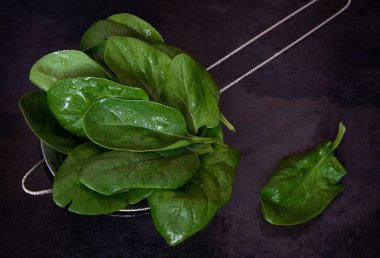 Siyah arka planda kevgire yıkanmış ıspanak..