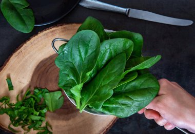 Kadın eli yeni yıkanmış ıspanakla kevgir tutuyor..