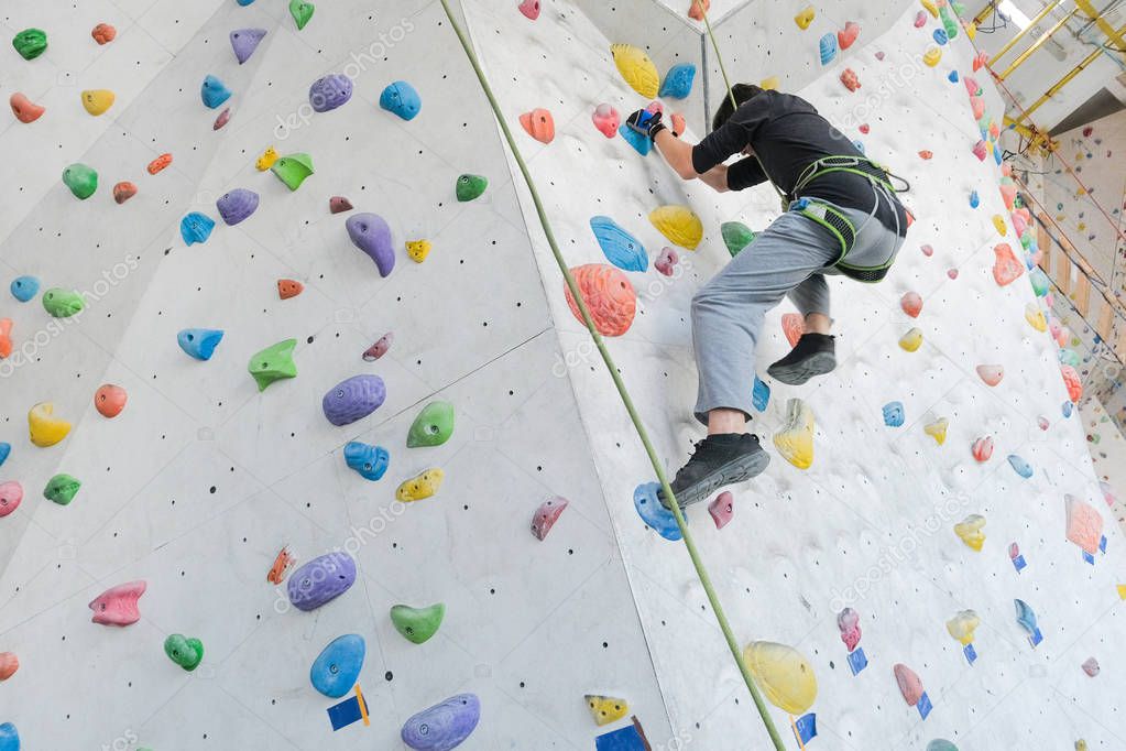 Sportsmen climbs boulder in a gym. A successful man climbing on climbing wall.                                          