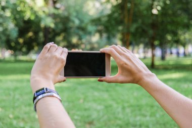 Kadın yeşil park Caddesi üzerinde dokunmatik ekran akıllı telefon kısa mesaj veya reklam içeriği için boş kopya alanı ekranlı holding.