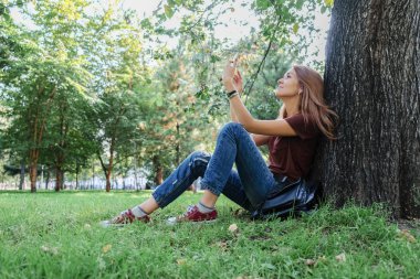 Genç başarılı kadın selfie doğa parkında yapıyor. Onların arkadaşları fotoğraflarını Smartphone'da hipsters.