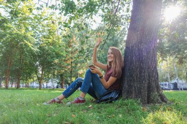 Genç başarılı kadın selfie doğa parkında yapıyor. Onların arkadaşları fotoğraflarını Smartphone'da hipsters.