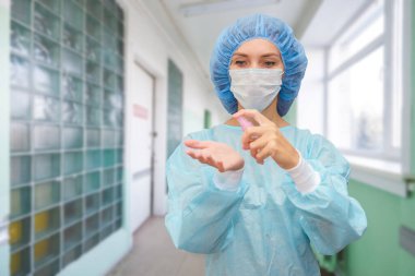 Kadın doktor ellerini antiseptik jelle tedavi ediyor. Önlüklü doktorun portresi..