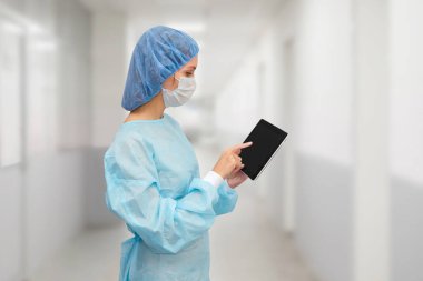 Tıbbi maskeli bir doktor dijital tablet hakkında bilgi verir.