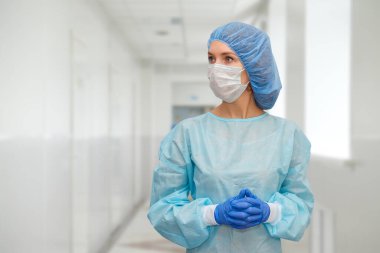 Önlüklü doktor portresi. Korunaklı şapkalı ve yüz maskeli bir kadın doktor. Koronavirüse karşı güvenlik önlemleri almış..