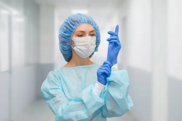 Portrait of doctor in scrubs. A female doctor in a protective cap and face mask in safety measures against the coronavirus.