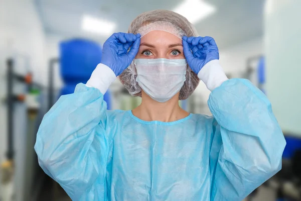 Portrait of doctor in scrubs. A female doctor in a protective cap and face mask in safety measures against the coronavirus.