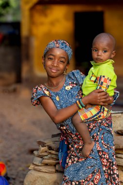 Kamerun 'da Fulani kardeşler, küçük erkek kardeşini kucaklayan abla, Afrika aile hayatının özünü, neşesini ve sevgisini yakalıyor..