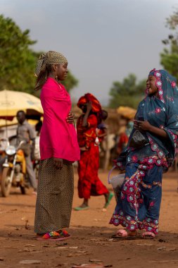 Kamerun pazarında iki kadın aynı kahkahayı paylaşıyor. Renkli kıyafetleri toplumsal hayatın neşesini ve canlılığını yansıtıyor..