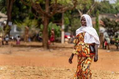 Afrikalı bir kadın, Ngaoundere 'de düzenlenen Uluslararası Kadın Günü' nde canlı geleneksel kıyafetler ve beyaz bir eşarp giyerek zarafetle yürüyor..