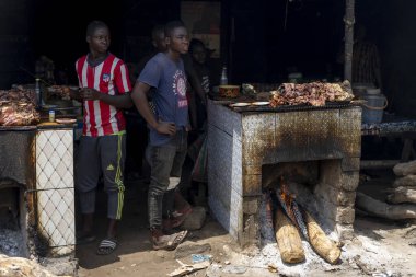 A street vendor in Cameroon grills meat at the market, capturing the authentic atmosphere of local cuisine and everyday life.