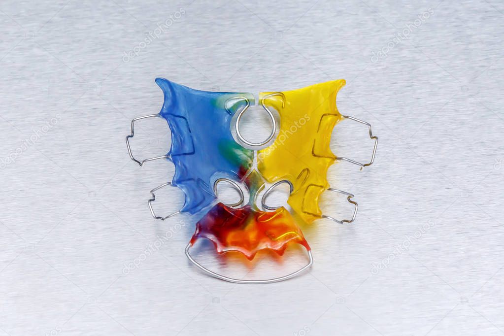 Colorful dental braces or retainer for teeth on metall background, closeup