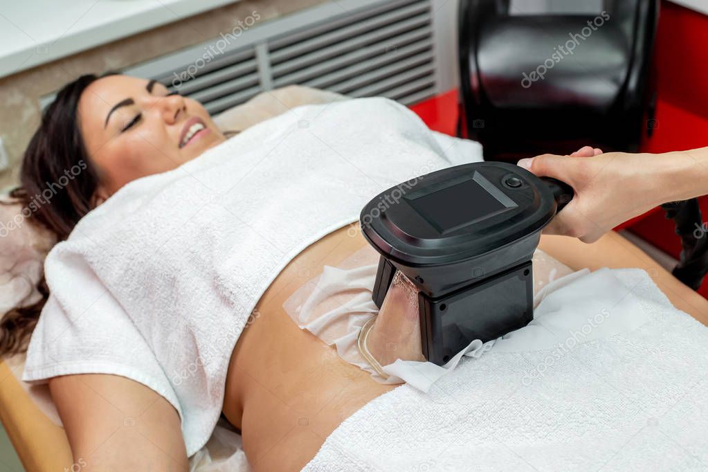 Woman getting cryolipolysis fat treatment procedure in professional cosmetic cabinet or spa center