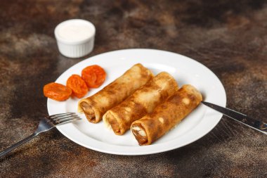 Süzme peynir ve kahverengi zemin üzerine kuru kayısı ile doldurulmuş krep