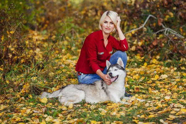 美丽的白种女孩在秋天森林或公园与沙哑的狗玩 — 图库照片