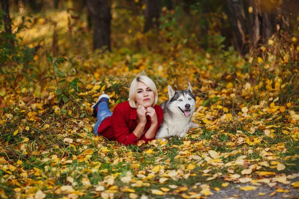 白人の女の子は美しい秋の森や公園でハスキー犬と遊ぶ — ストック写真