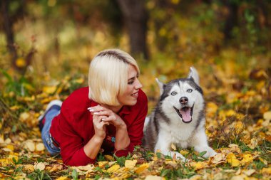 Güzel beyaz kız sonbahar orman veya park husky köpek ile çalış