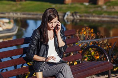 Parkta oturan cep telefonunuzla gülümseyen yakışıklı beyaz kadın