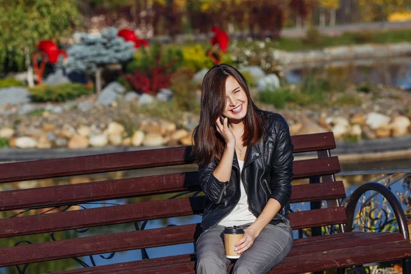 Handsome smiling caucasian woman with smartphone sitting in park