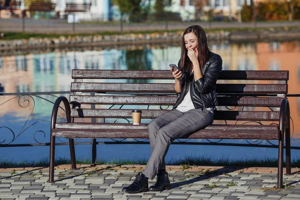 Parkta oturan smartphone ile gülümseyen yakışıklı beyaz kadın