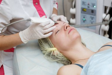 Yordam yüz ile güzellik salonda ultrasonik yüzey temizlik yaparken güzellik uzmanı