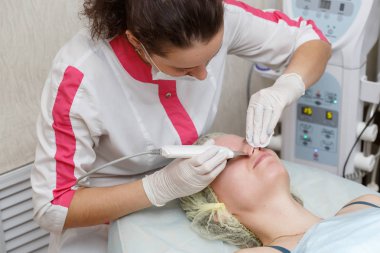 Yordam yüz ile güzellik salonda ultrasonik yüzey temizlik yaparken güzellik uzmanı