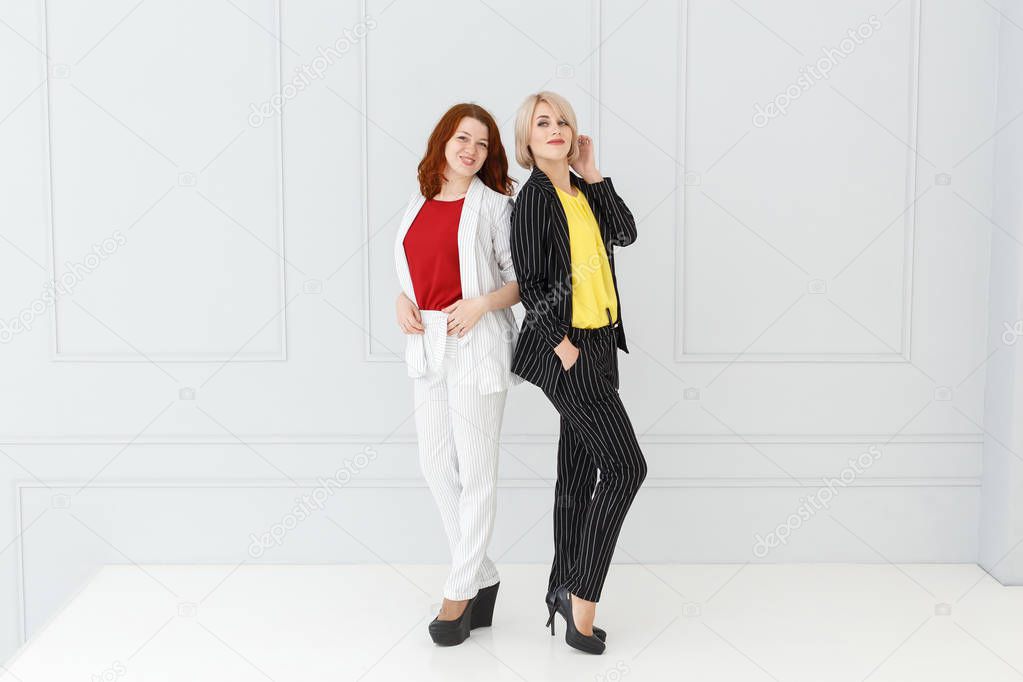 Fashion portrait of women in white and black suit on light background
