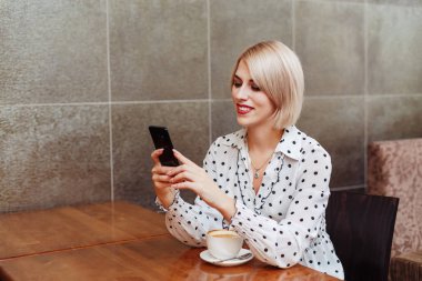 Genç gülümseyen kadın smartphone vasıl seyir Cafe