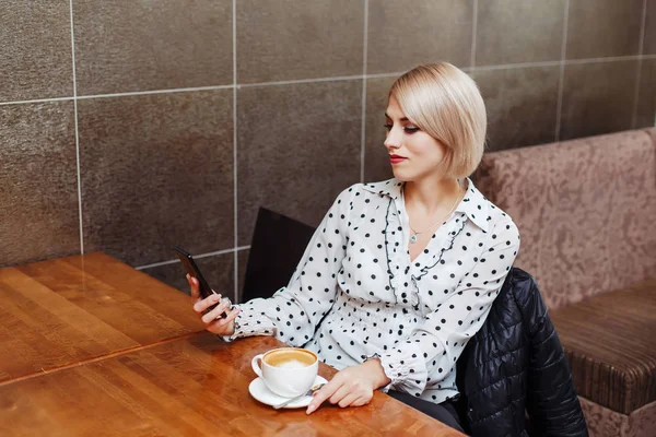 Smartphone vasıl seyir kafede oturan genç kadın