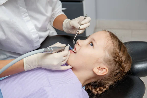 Child girl having professional dental cleaning or polishing in dentist office