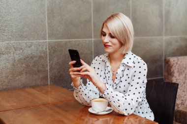 Genç gülümseyen kadın smartphone vasıl seyir Cafe