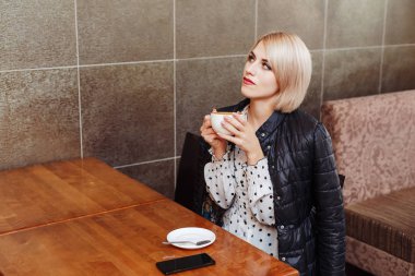 Sarışın genç kadın cafe latte kahve içme ve düşünme