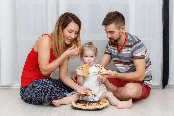 Family eating pizza. Father, mother and daughter sitting at home