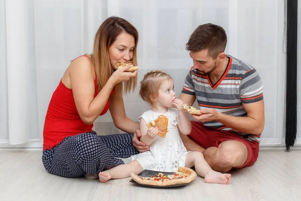 Family eating pizza. Father, mother and daughter sitting at home