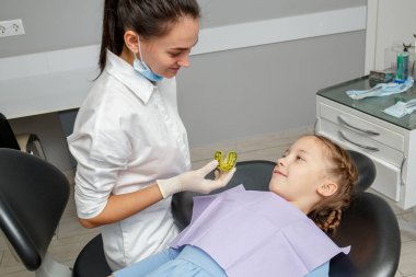 Çocuk kız ortodontist randevu sahip. Kadın doktor dişçi ofisinde