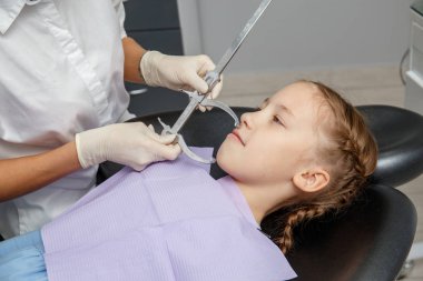 Çocuk kız ortodontist randevu sahip. Kadın doktor dişçi ofisinde