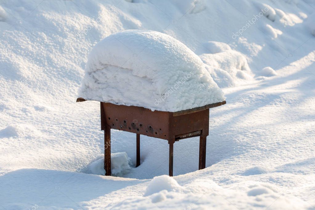 Metal bbq brazier covered with pile of snow, winter outdoors concept