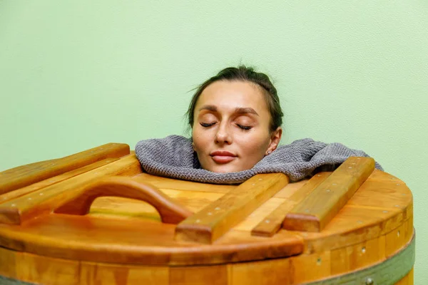 Woman relaxing in cedar spa barrel body rejuvenation and relax sauna