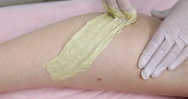 Epilasyon güzellik salonda ayak üzerinde sugaring olan bir kadın. Elinde bir güzellik saç kaldırma işlemi şeker yapma yapıştırın, portre