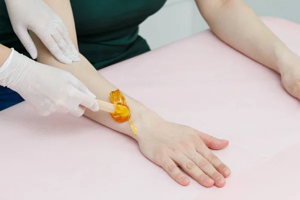 Esteticista aplicando depilación azucarada en los brazos, depilación para mujer — Foto de Stock