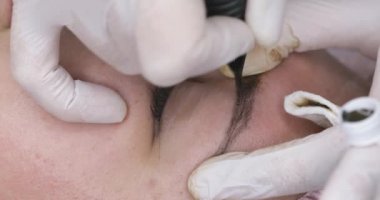 Kalıcı makyaj, kaşların dövme. Güzellik salonunda kadın için makine ile makyaj uygulayan Kozmetolog, makro