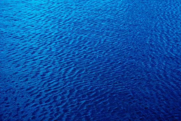 Glanzende donker blauwe golvende wateroppervlak rimpel achtergrond — Stockfoto