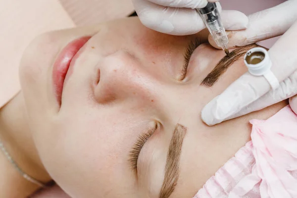 Permanent makeup, tattooing of eyebrows. Cosmetologist applying make up
